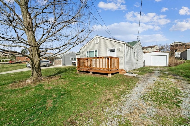 back of property with a lawn, a deck, driveway, an outdoor structure, and a garage