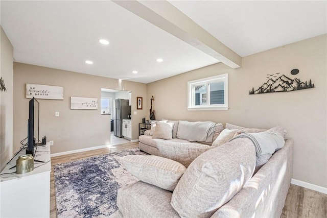 living room featuring recessed lighting, baseboards, beam ceiling, and light wood finished floors