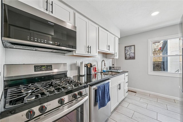 kitchen with baseboards, recessed lighting, white cabinets, stainless steel appliances, and a sink