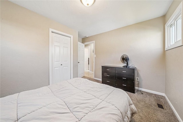 carpeted bedroom with visible vents, baseboards, and a closet