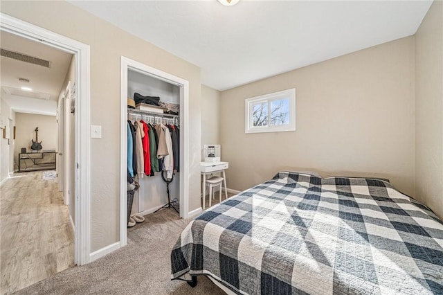 bedroom with a closet, visible vents, light colored carpet, and baseboards
