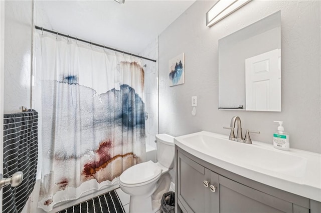 bathroom featuring toilet, shower / bath combo with shower curtain, vanity, and a textured wall