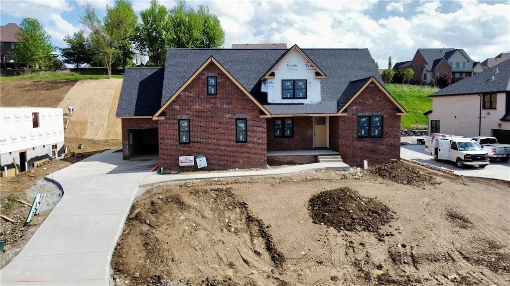 view of front of property with brick siding, covered porch, an attached garage, concrete driveway, and roof with shingles