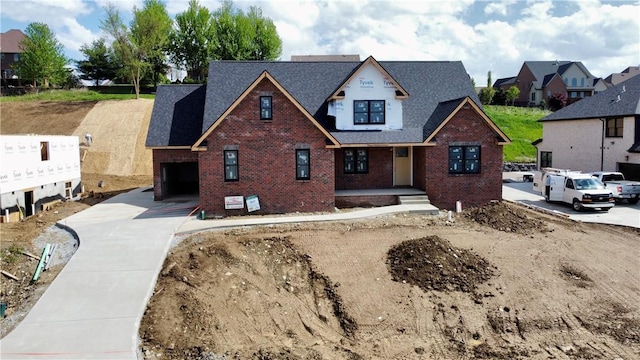 view of front of property with brick siding, covered porch, an attached garage, concrete driveway, and roof with shingles