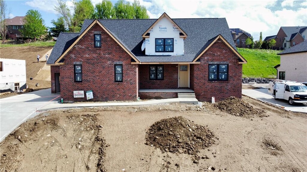 view of front facade with a shingled roof and brick siding