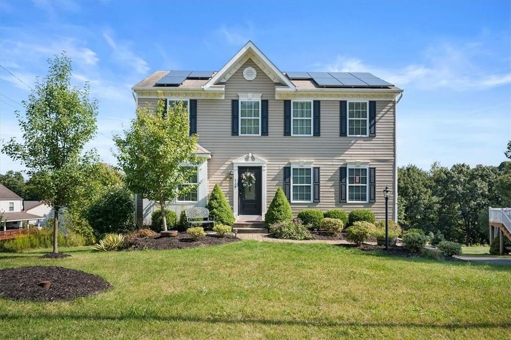 colonial house featuring solar panels and a front yard