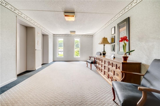 living area featuring a textured ceiling, carpet floors, elevator, a textured wall, and baseboards
