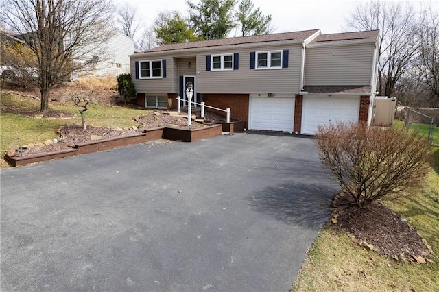 split foyer home with an attached garage, fence, brick siding, and driveway