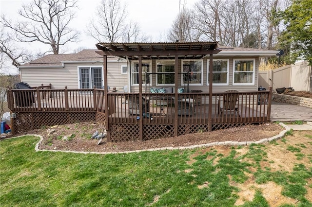 rear view of property featuring a wooden deck, fence, a pergola, and a lawn