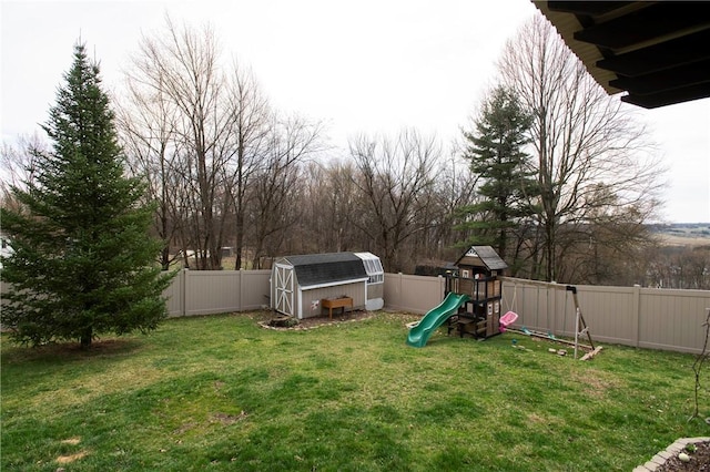 view of yard with an outdoor structure, a playground, a fenced backyard, and a shed