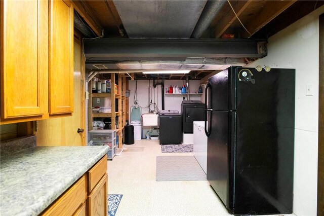 unfinished below grade area with separate washer and dryer, freestanding refrigerator, and a sink