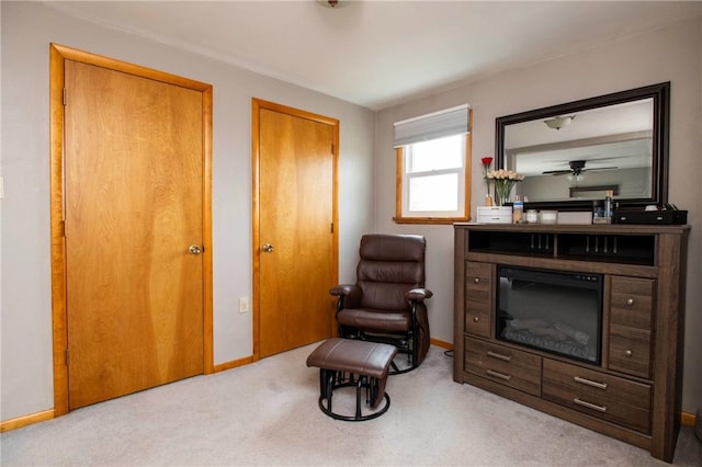 living area with a glass covered fireplace, carpet flooring, and baseboards