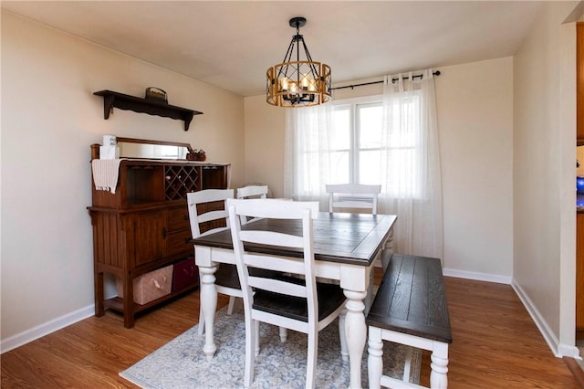 dining room with baseboards, a notable chandelier, and wood finished floors