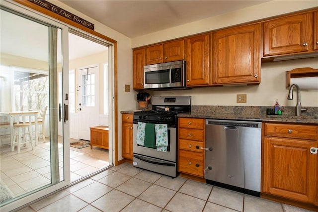 kitchen featuring a sink, light tile patterned floors, brown cabinetry, and stainless steel appliances