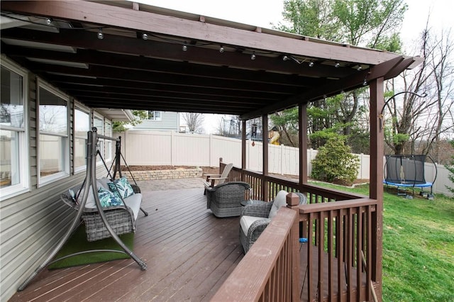 deck featuring a yard, a trampoline, and a fenced backyard