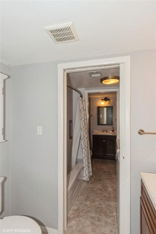 full bath featuring visible vents, toilet, vanity, and shower / bath combo