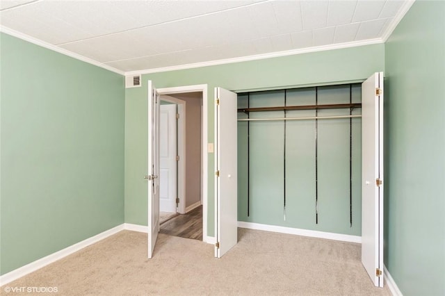 unfurnished bedroom with baseboards, visible vents, a closet, light carpet, and crown molding