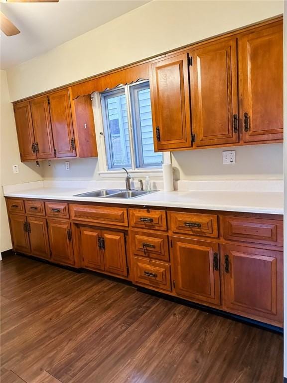kitchen featuring light countertops, dark wood-type flooring, a sink, ceiling fan, and brown cabinetry