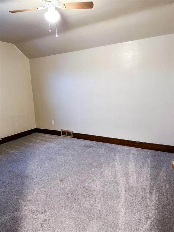spare room with vaulted ceiling, baseboards, visible vents, ceiling fan, and carpet