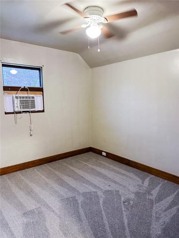 carpeted spare room featuring cooling unit, a ceiling fan, baseboards, and lofted ceiling