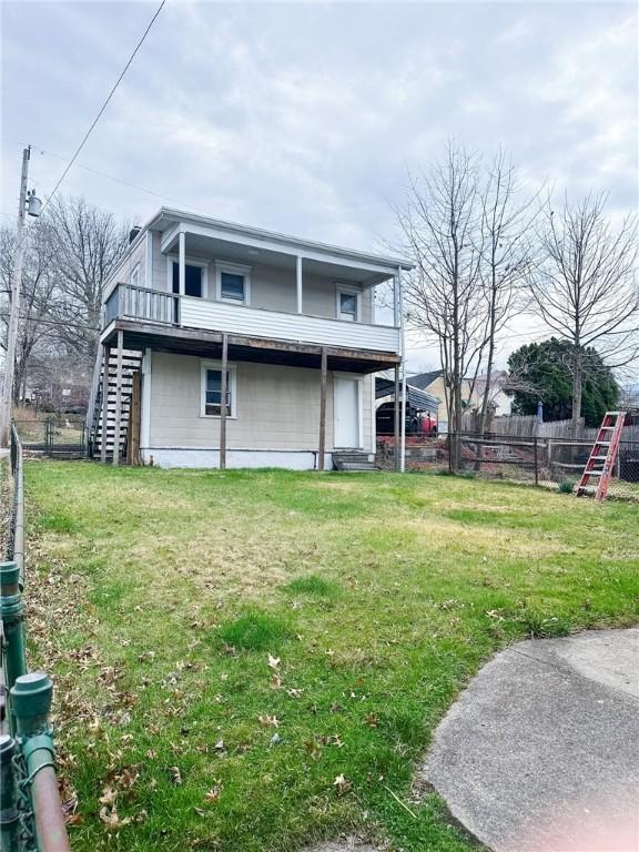 back of property with fence, stairway, and a yard