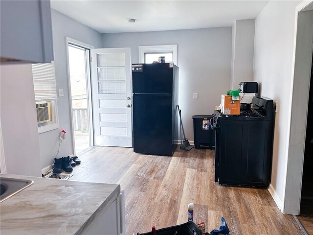 kitchen featuring freestanding refrigerator, washer / clothes dryer, baseboards, and light wood-style floors