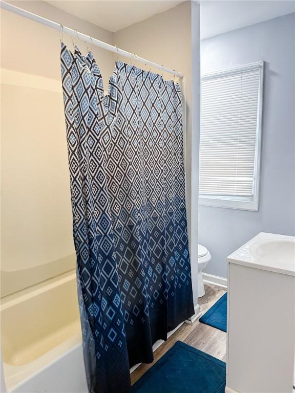 bathroom featuring toilet, vanity, shower / bath combo, and wood finished floors