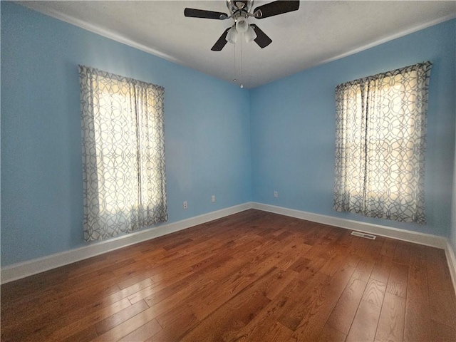 empty room with baseboards, visible vents, ceiling fan, and wood-type flooring