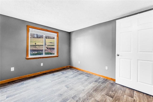 unfurnished room featuring baseboards, a textured ceiling, and wood finished floors