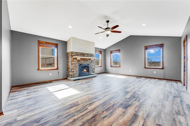 unfurnished living room featuring vaulted ceiling, a healthy amount of sunlight, light wood-type flooring, and ceiling fan