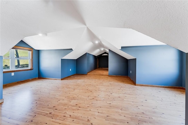 bonus room with a textured ceiling, lofted ceiling, and wood finished floors