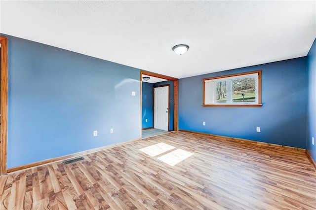 empty room featuring visible vents, baseboards, and wood finished floors