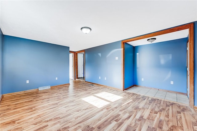 spare room featuring visible vents, light wood-style flooring, and baseboards