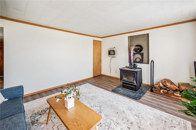 living area with heating unit, ornamental molding, a wood stove, and wood finished floors