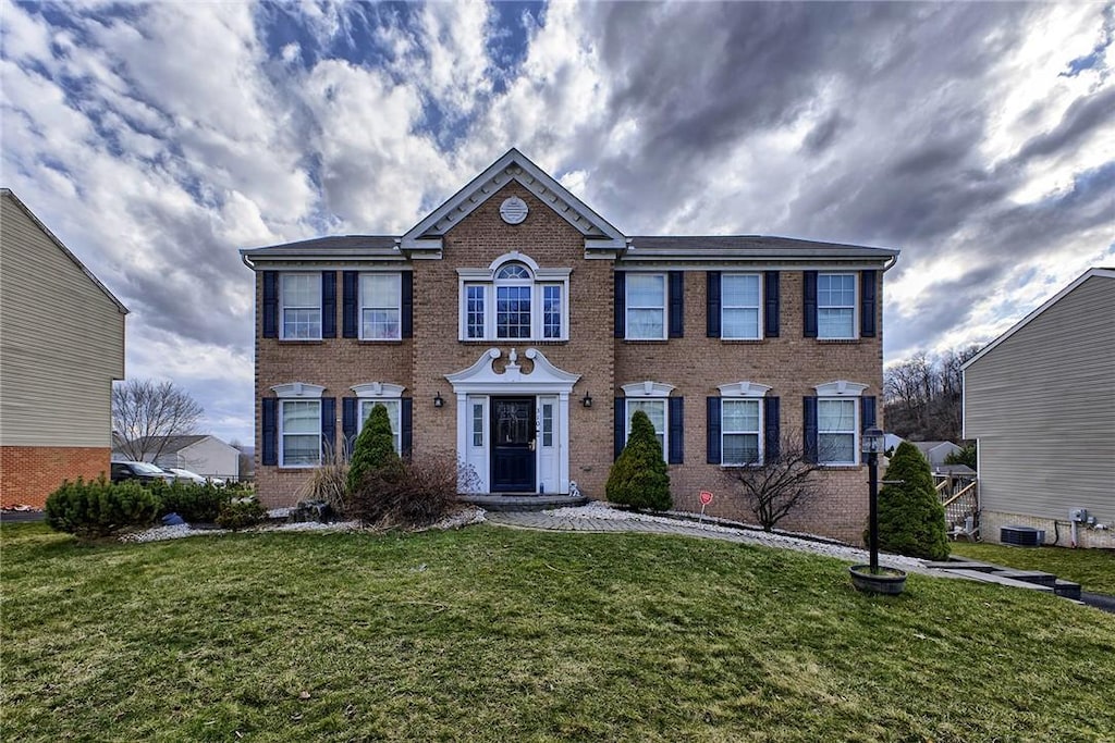 colonial inspired home with a front lawn and brick siding