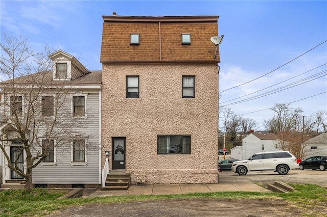 view of front of house with stucco siding, a shingled roof, and entry steps