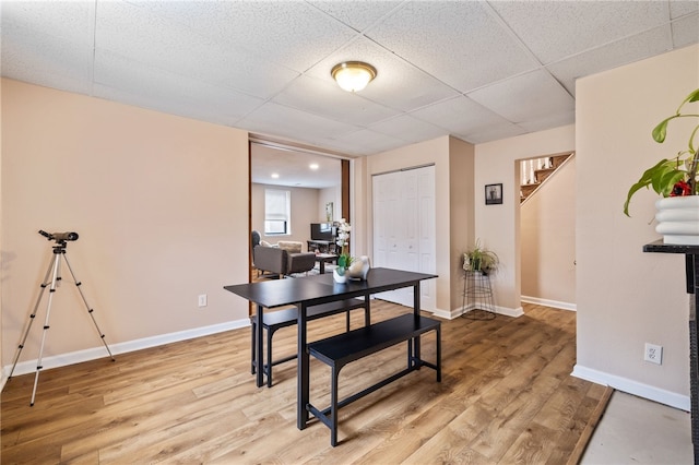 office space with a drop ceiling, light wood-style flooring, and baseboards