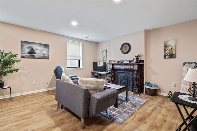 living room with baseboards, a fireplace, and light wood finished floors