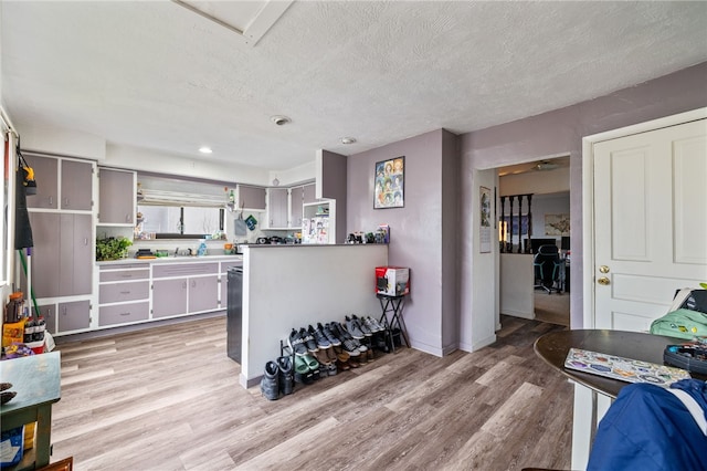 kitchen with light wood-type flooring, light countertops, and a textured ceiling
