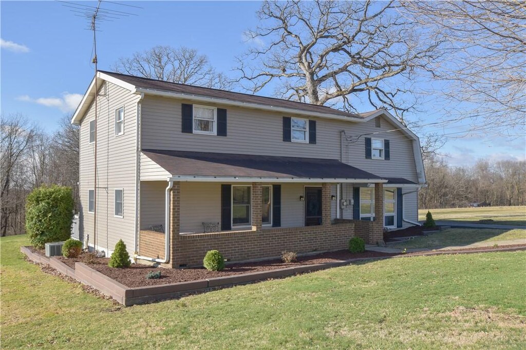 traditional home featuring a porch, brick siding, and a front yard