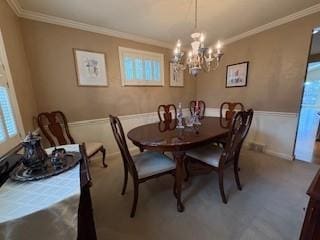 dining area featuring a healthy amount of sunlight, a chandelier, wainscoting, and crown molding