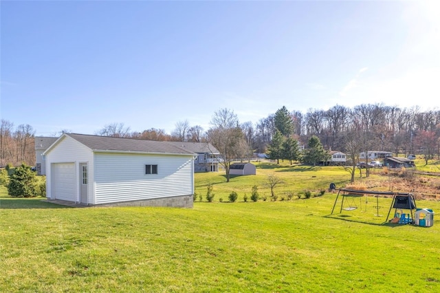 view of yard featuring an outdoor structure, a playground, and a garage