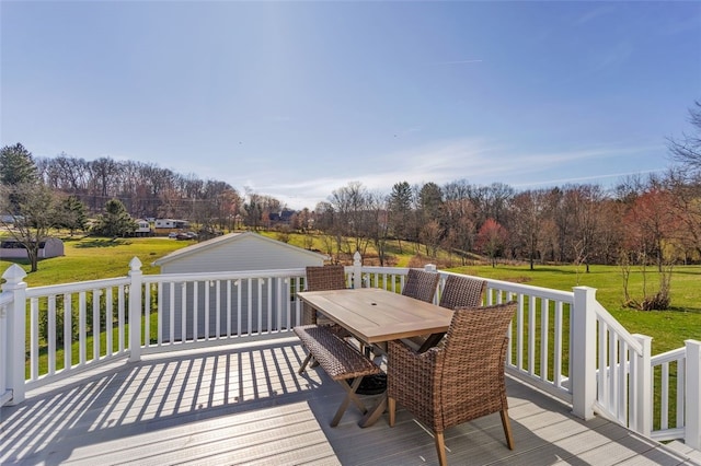 wooden deck featuring a lawn and outdoor dining area