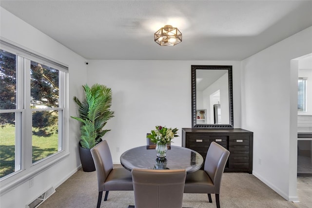 dining room with visible vents, baseboards, and light colored carpet