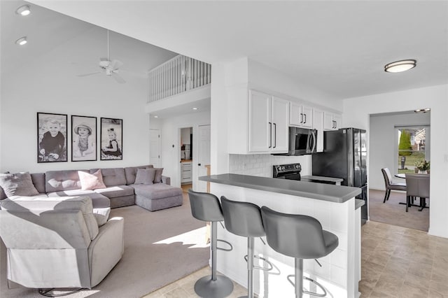 kitchen with range with electric cooktop, ceiling fan, white cabinets, stainless steel microwave, and light colored carpet