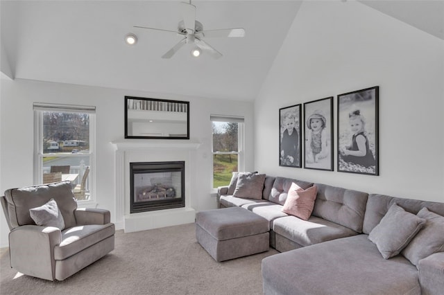 carpeted living area featuring a glass covered fireplace, high vaulted ceiling, and ceiling fan