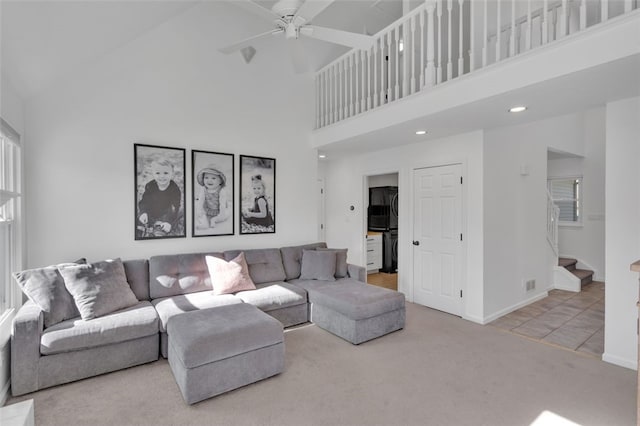 living area featuring stairway, carpet, a high ceiling, baseboards, and ceiling fan