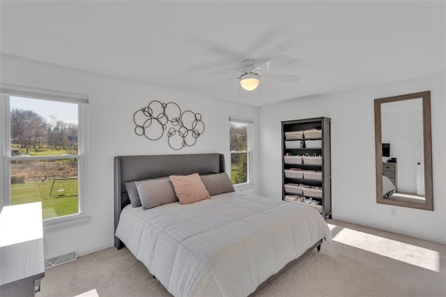 bedroom featuring visible vents, multiple windows, light colored carpet, and ceiling fan