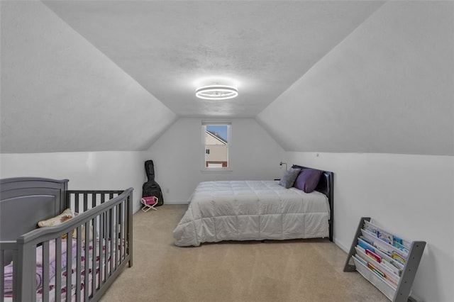 bedroom featuring lofted ceiling, carpet, baseboards, and a textured ceiling