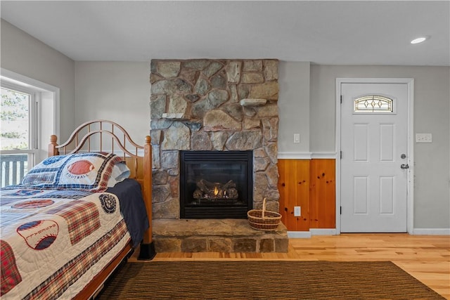 bedroom with a stone fireplace and wood finished floors